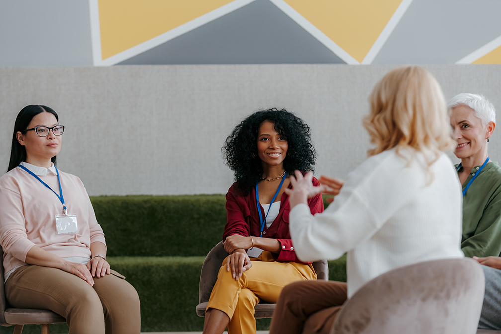 Group of adult women talking in a circle, listening to one person at a time.